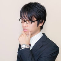 メガネをかけて考え込むスーツ姿の男性の写真