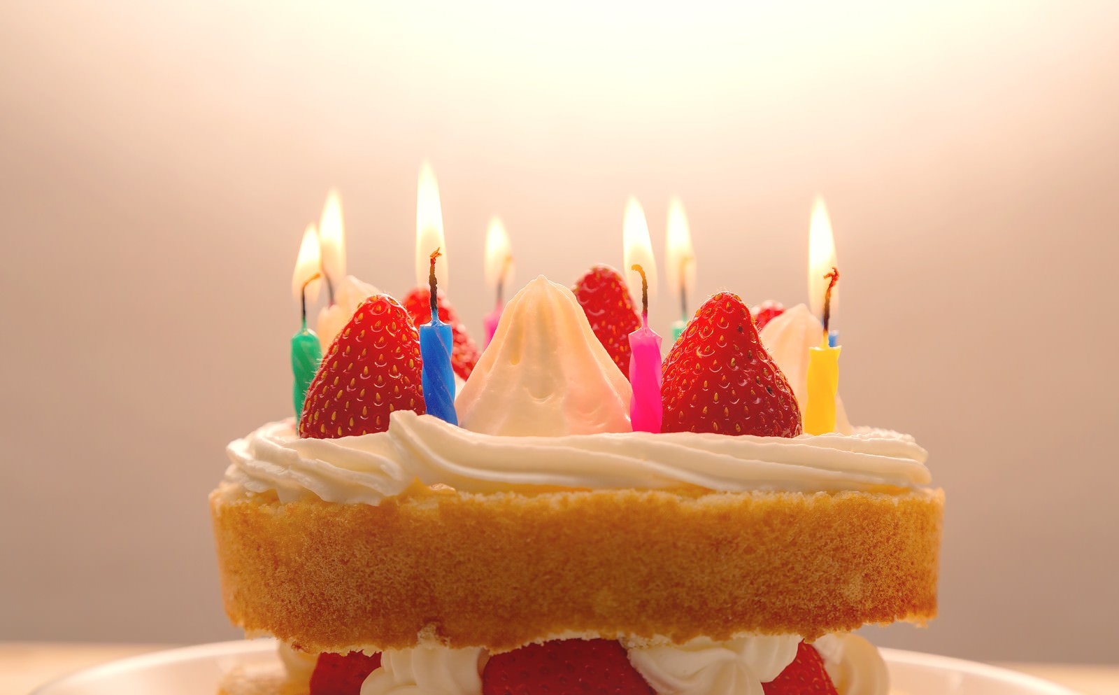 イチゴとろうそくに火が灯る誕生日ケーキ