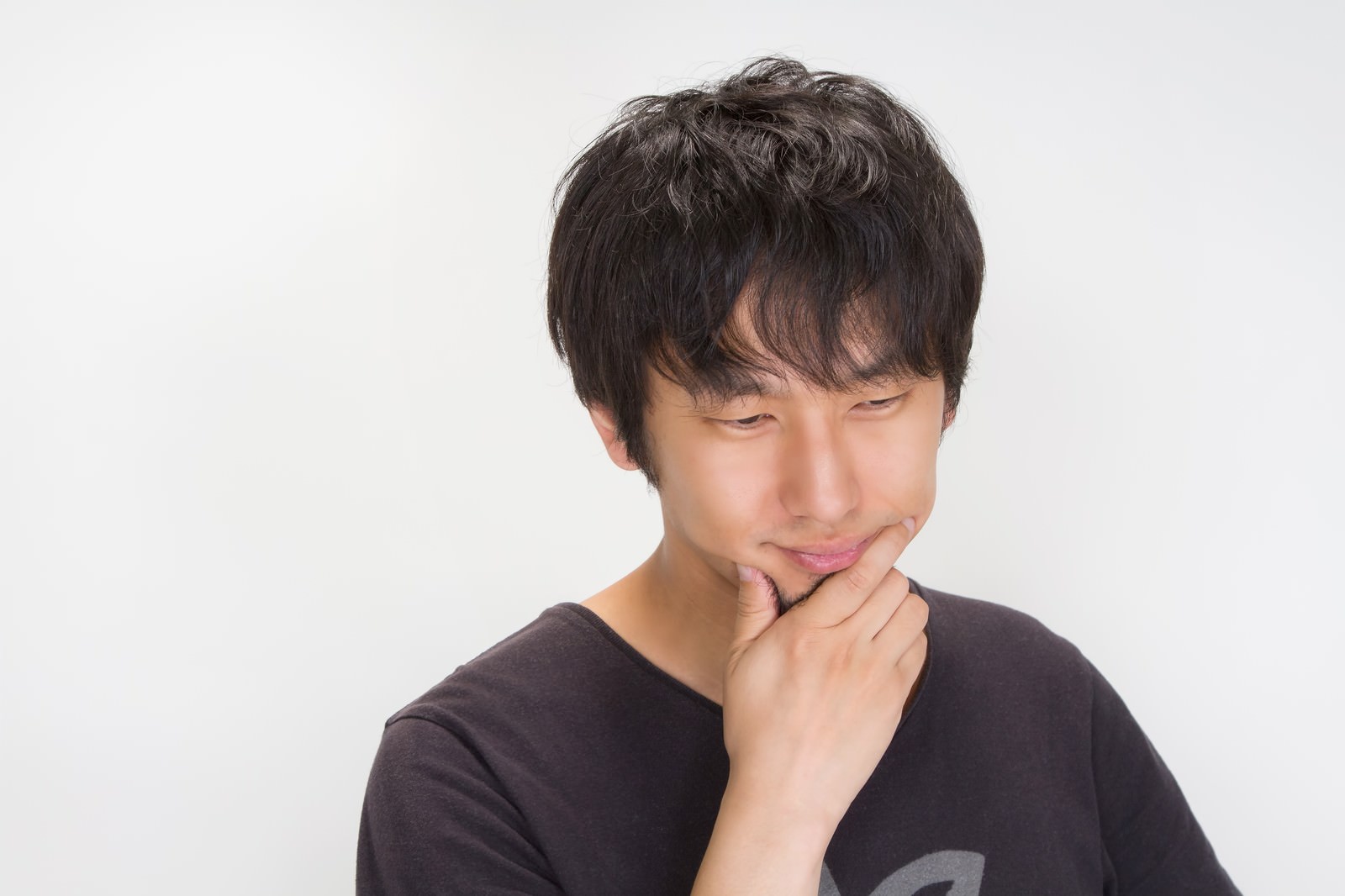 目を閉じて口元に手を当てる考える男性［モデル：大川竜弥］