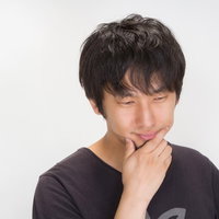 目を閉じて口元に手を当てる考える男性の写真