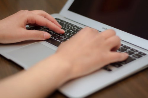 ノートパソコンのキーボードを打つ両手