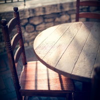 屋外のタイル床に置かれた木製椅子と日差しの影の写真