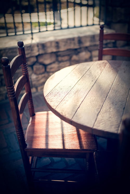 屋外のタイル床に置かれた木製椅子と日差しの影