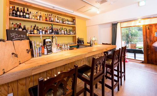 窓から光が差すバーカウンター席と酒瓶棚