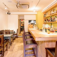 木製カウンターと酒瓶が並ぶオーガニック料理店の店内の写真