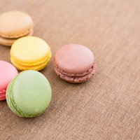 ベージュの布の上に並ぶカラフルなマカロンの写真