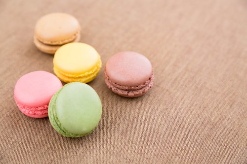 ベージュの布の上に並ぶカラフルなマカロン