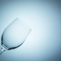 青白い光の中で傾いた透明なワイングラスの写真