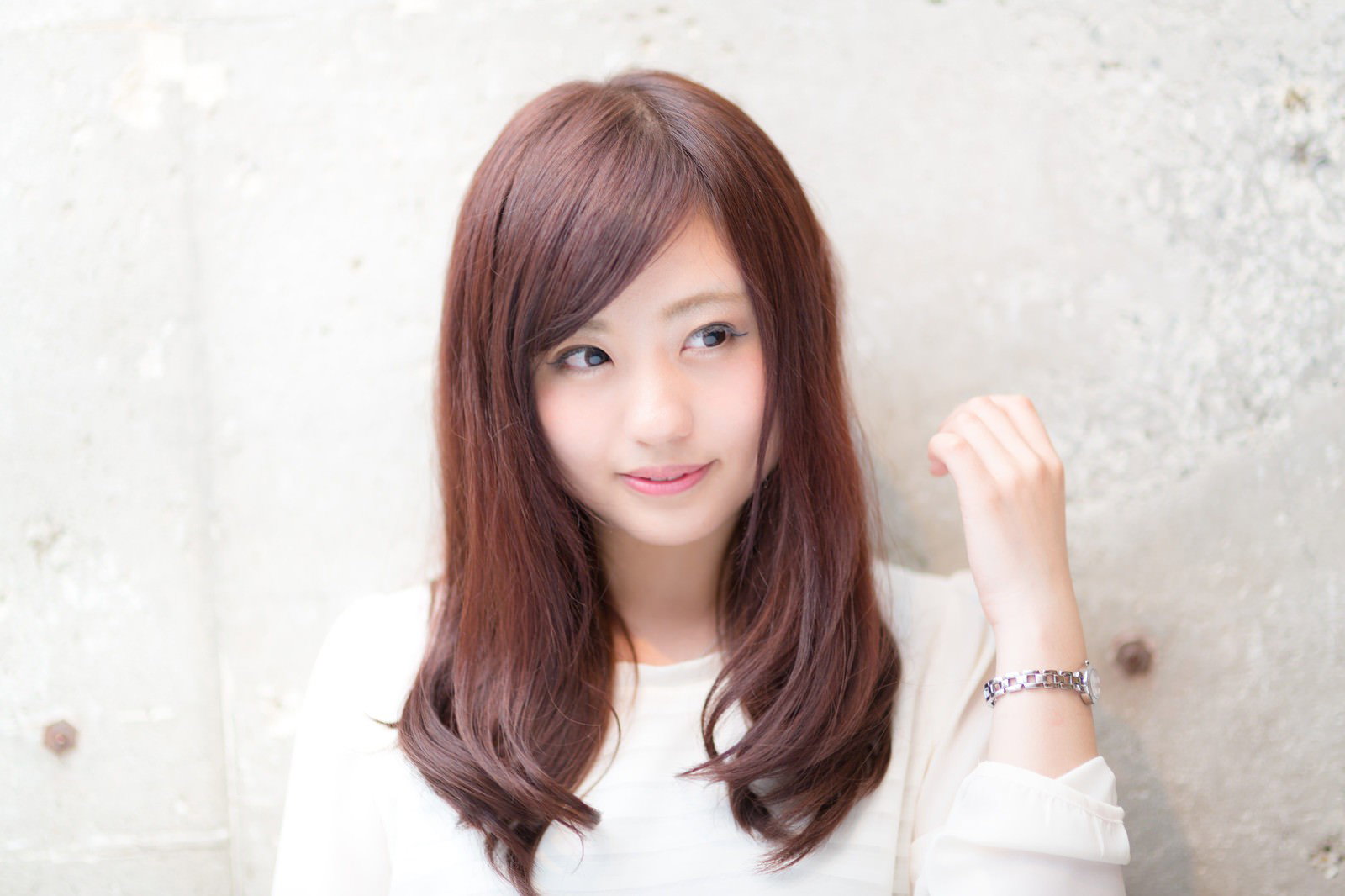 白いトップスにブラウンロングヘアの女性が首に手をあてて横を向いている［モデル：河村友歌］