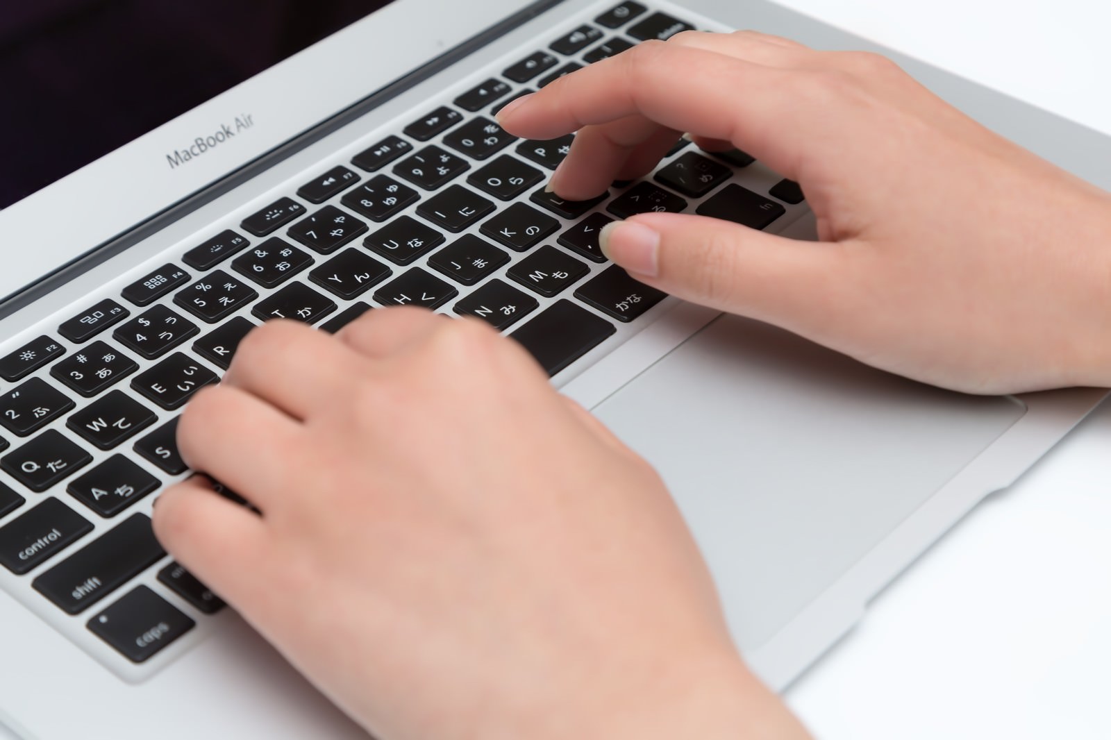 MacBook Airのキーボードをタイプする両手