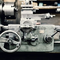 円形ハンドルとレバーが並ぶ工場の汎用旋盤の写真