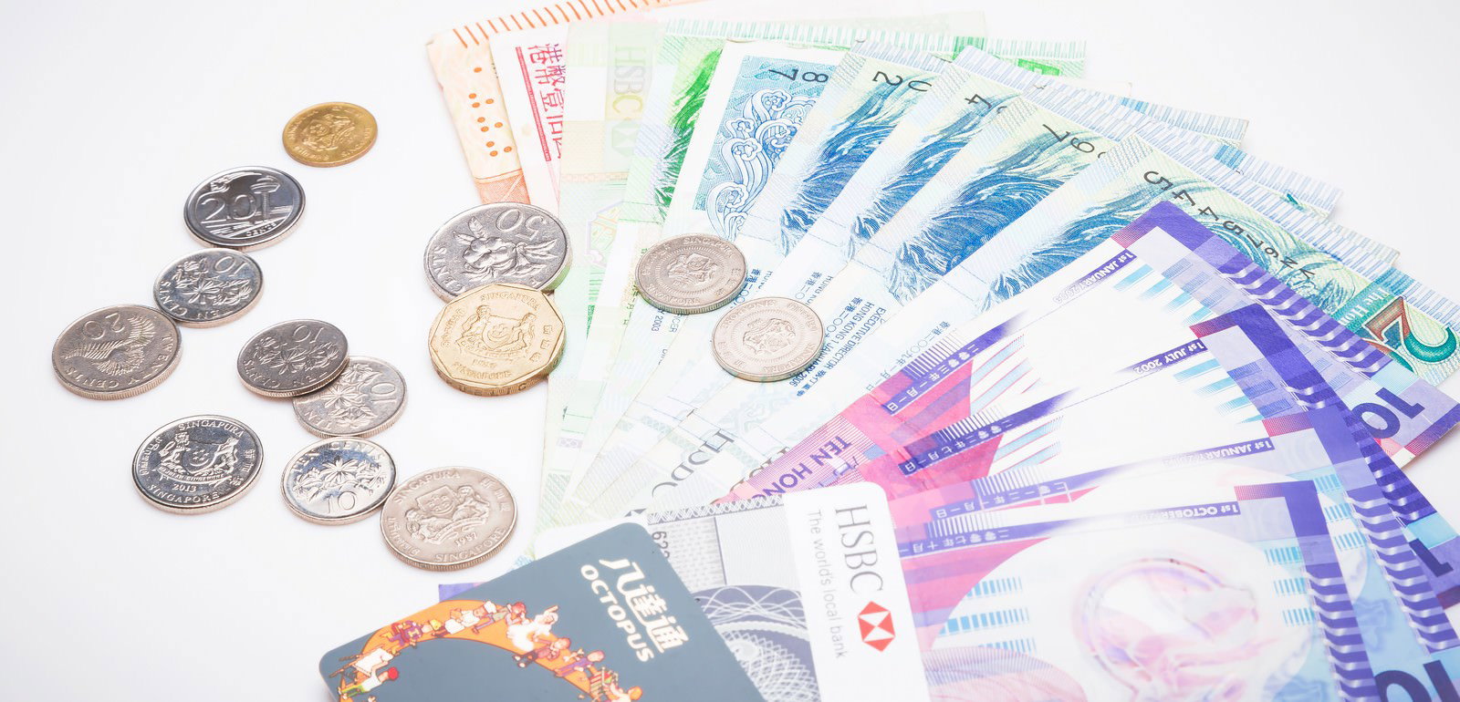 白背景に扇状に広げた外貨紙幣とシンガポールドルの硬貨、HSBCクレジットカード