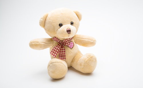赤と白のチェック柄リボンを結んだベージュのくまのぬいぐるみ