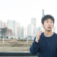 都会の空き地でポテトチップスを食べたそうにこちらを見ている男性の写真