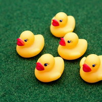 緑の布の上に並ぶ黄色いアヒルのおもちゃ5個の写真