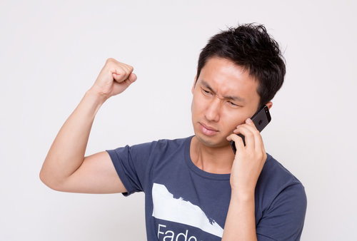 スマートフォンで電話しながら拳を上げる男性