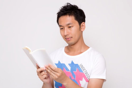 本を開いて読書する白Tシャツの男性