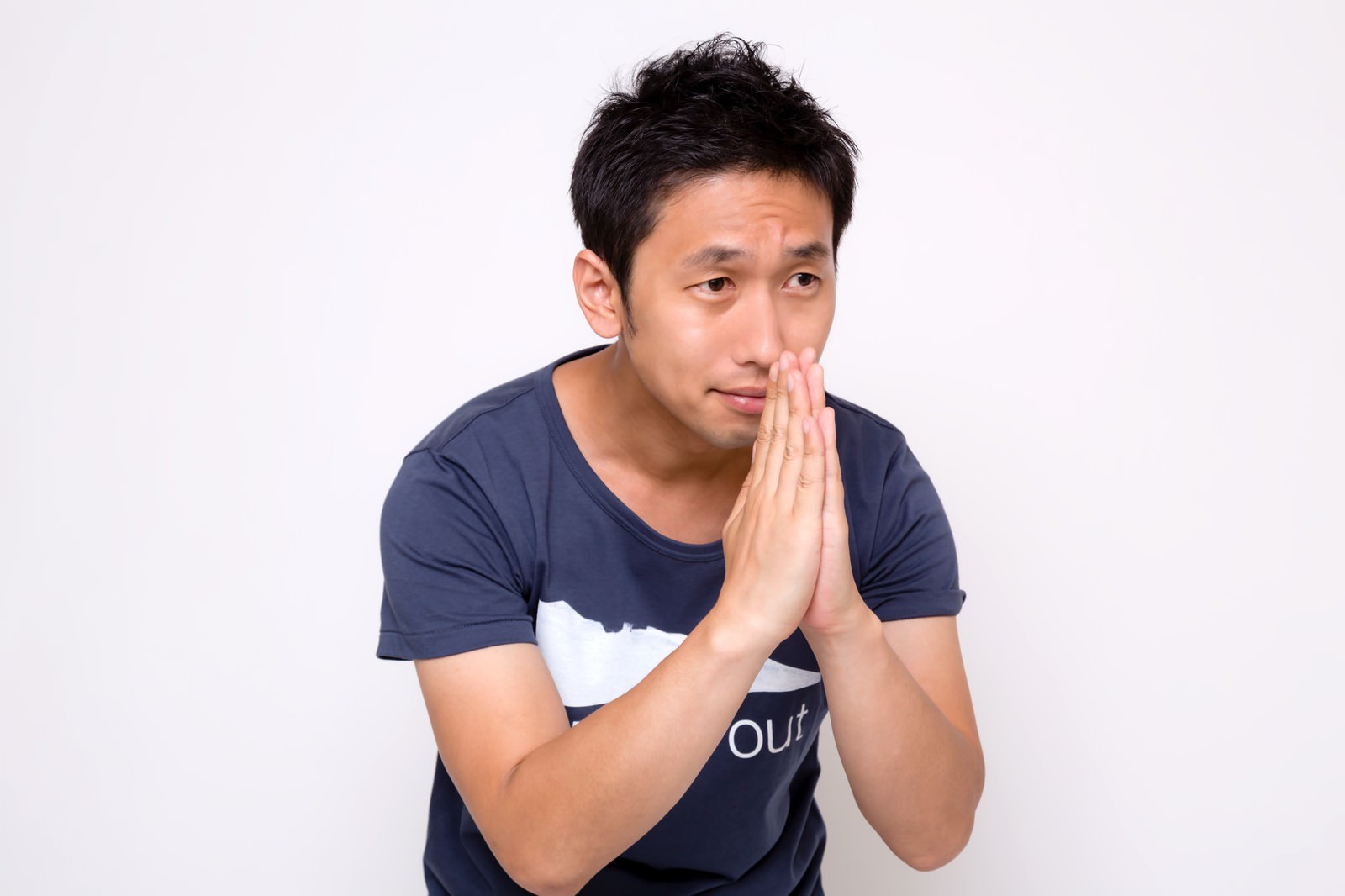 両手を合わせてごめんなさいと謝る男性［モデル：大川竜弥］
