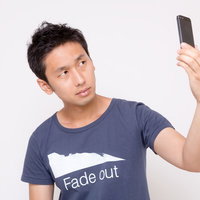 スマホを持ち上げて自撮りする男性の写真