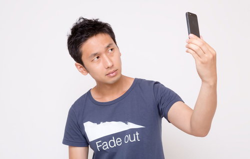 スマホを持ち上げて自撮りする男性