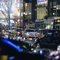 夕暮れから夜の渋谷駅前の道路を走る車やタクシーの光跡の写真