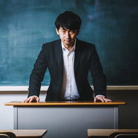 黒板の前で経典を読み上げる不気味な高校教師の写真