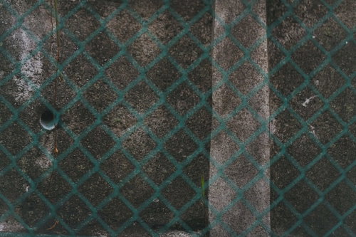 錆びた緑色フェンスとコンクリート壁の劣化テクスチャー