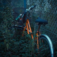 荒れ果てた場所に置き捨てられたオレンジの自転車の写真