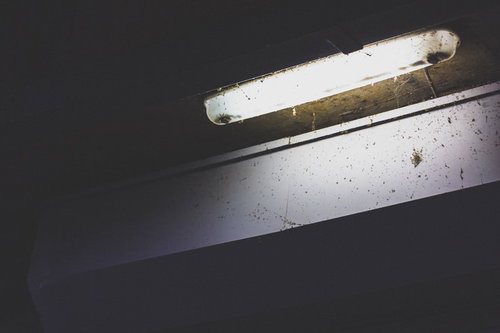 薄汚れた街灯の電気部分と配線、錆びた支持金具の写真