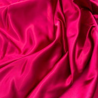 波打つように折り目が広がるピンク色のサテン生地の写真