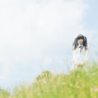 草原に立つブラウスのツインテールの女性の写真