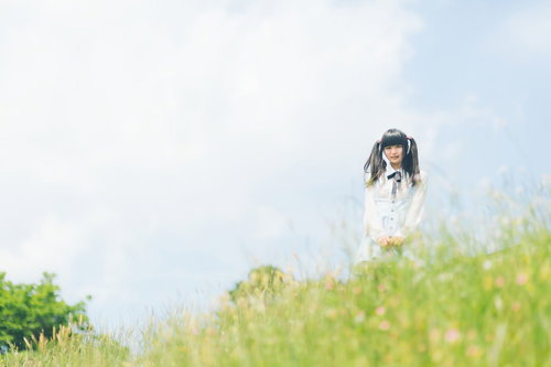 草原に立つブラウスのツインテールの女性