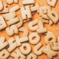 オレンジ色の布の上に並ぶO・P・R・Sなどのアルファベットクッキーの写真