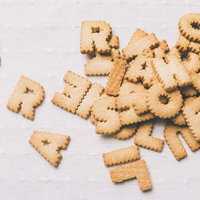 白い布の上に散らばるアルファベット型の焼き菓子クッキーの写真