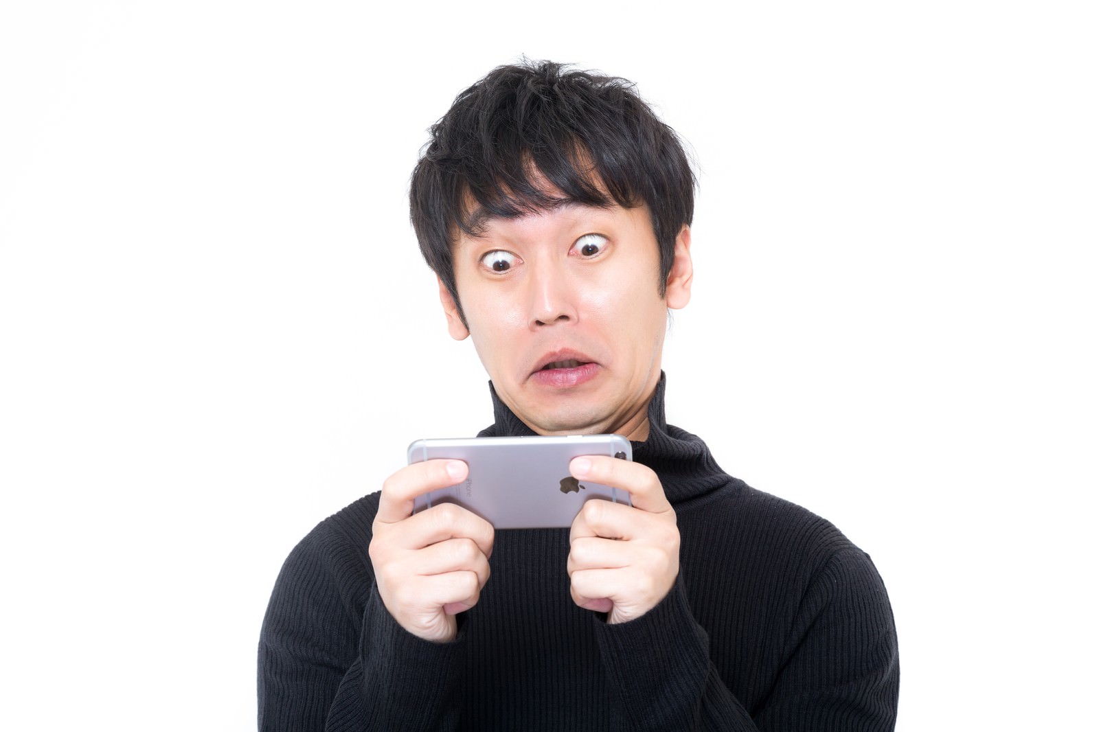 スマートフォンを持って驚いた表情の男性が驚愕している［モデル：大川竜弥］