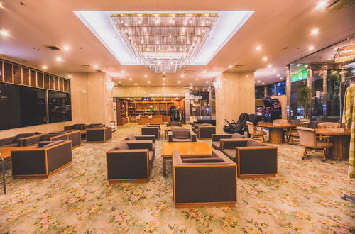 花柄の絨毯にソファとテーブルが配置されたシャンデリアのホテルロビー