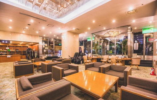 シャンデリアとガラスの仕切りがあるソファが並ぶホテルのロビー