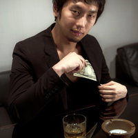 財布から万札を取り出す黒スーツの男性の写真