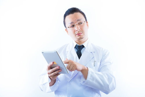 タブレットで患者情報を確認する白衣のドクター
