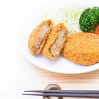 白い皿に揚げ物とキャベツの千切りとブロッコリーを盛り付けの写真