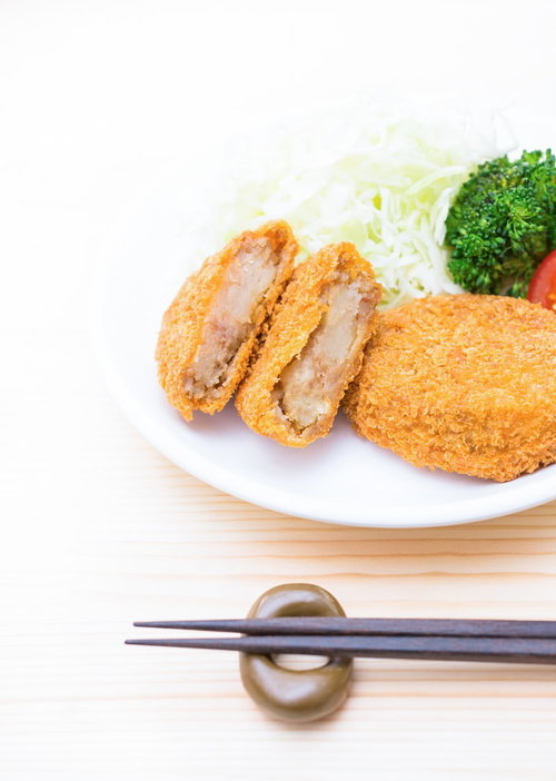 白い皿に揚げ物とキャベツの千切りとブロッコリーを盛り付け