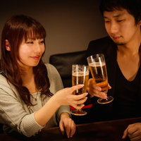 グラスを持って向かい合う男女の乾杯シーンの写真