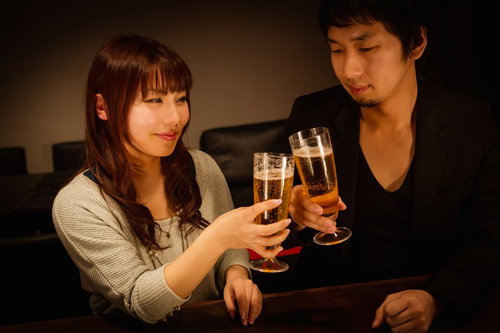 グラスを持って向かい合う男女の乾杯シーン