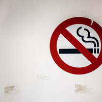 白い壁に掲示された赤い円と斜線の禁煙マークの写真