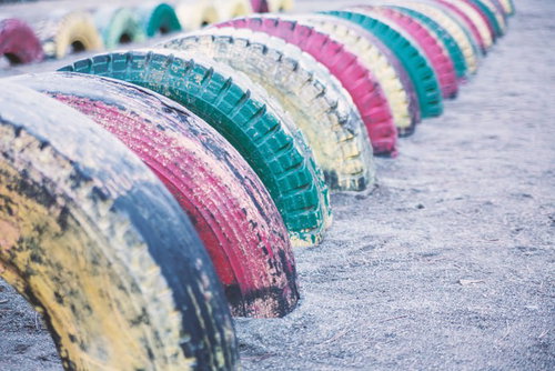 砂の地面に半分埋められたカラフルに塗装された古いタイヤの遊具