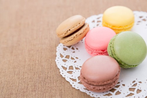レースペーパーの上に並んだパステルカラーのマカロン