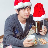 サンタ帽子を被りカップと食品トレイを持つ独りきりの男性の写真