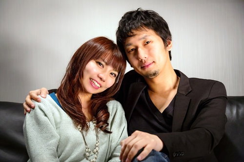 黒いソファに並んで座る男女