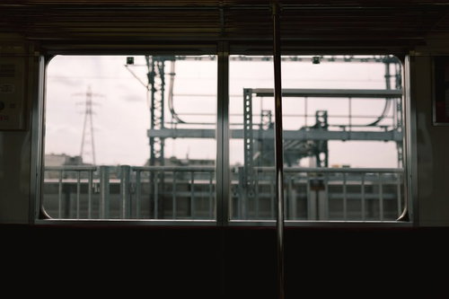 電車内の窓から見える駅ホームと鉄道施設