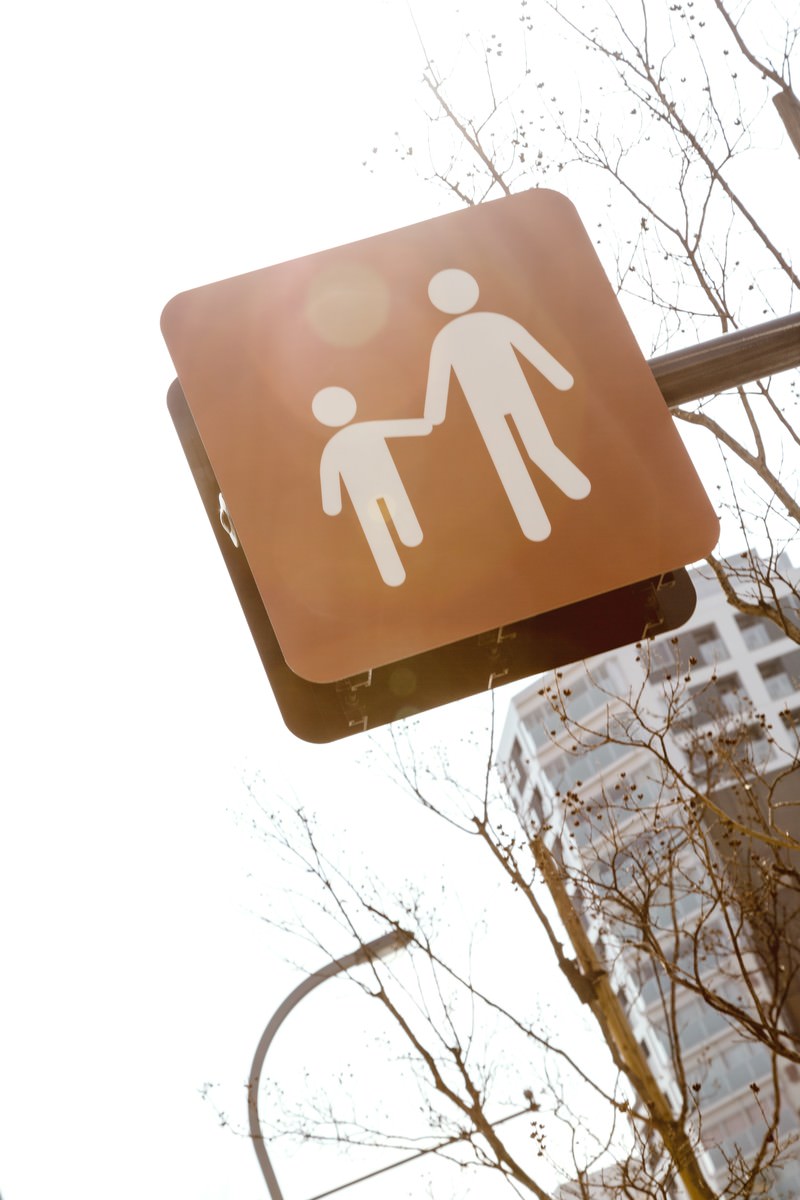 親子で手をつなぎながら歩く人物を示した茶色い標識